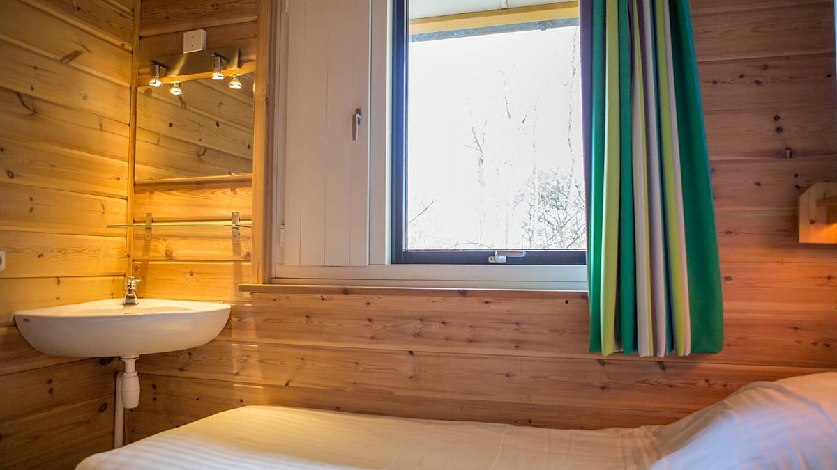 Villa vakantiehuisje 6 persoons slaapkamer met de 2 boxpringbedden los van elkaar met zicht op het bed onder het raam en aan het voeteneinde in de hoek een wastafel vakantiepark Tjermelan Oosterend Terschelling